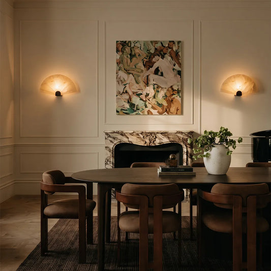 Scalloped wall sconce pair installed above a dining room sideboard with soft decorative lighting.