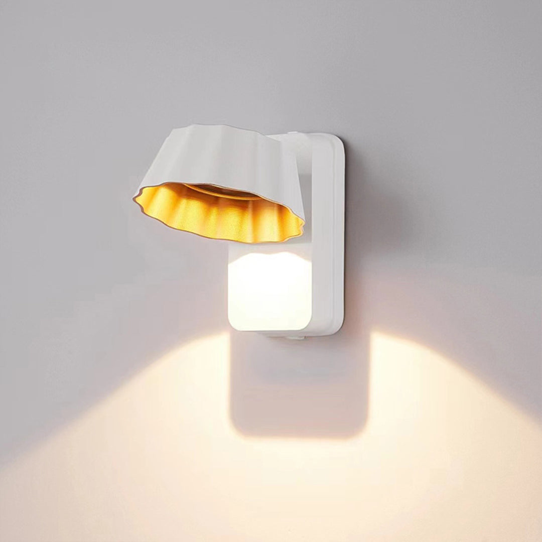 White sculptural wall sconce with unique curved design casting geometric light patterns