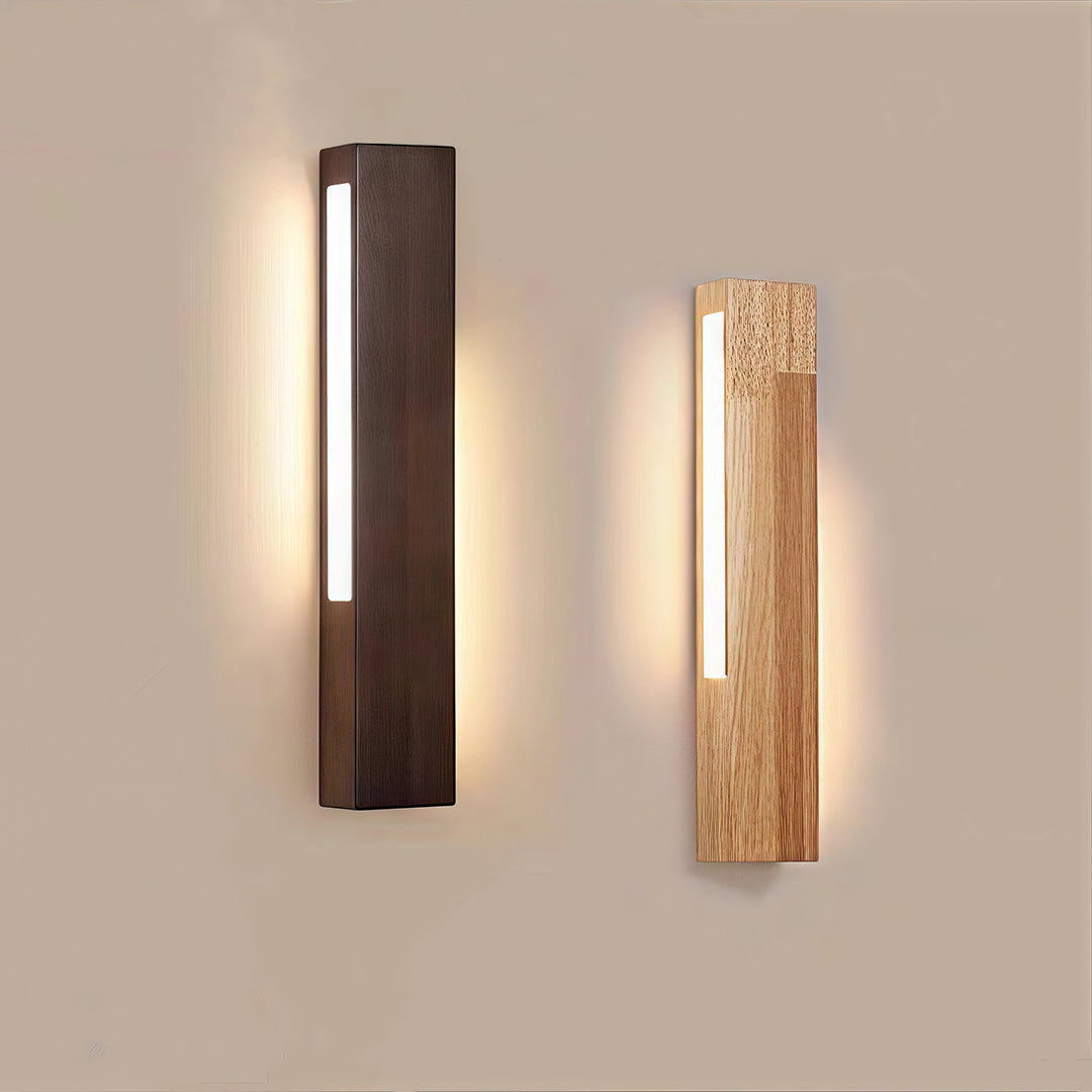 Dark brown wood Japanese wall light providing vertical LED illumination in a bedroom with wooden furniture. 