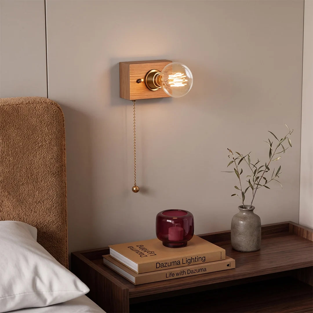 Retro bedside wall light above a bedside table, glowing warmly beside a bed and simple decor.