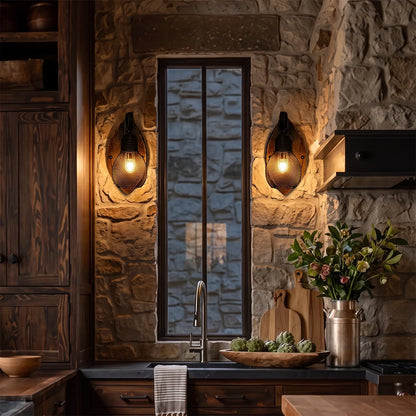 Rustic farmhouse wall sconces flanking a glass door in a warm kitchen, featuring wood backplates and textured glass bulbs on a stone wall.