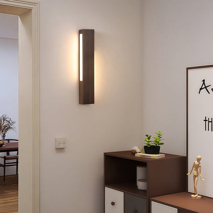 Slim Japanese wall light with a long dark wooden frame, mounted next to a doorway to provide discreet hallway lighting.